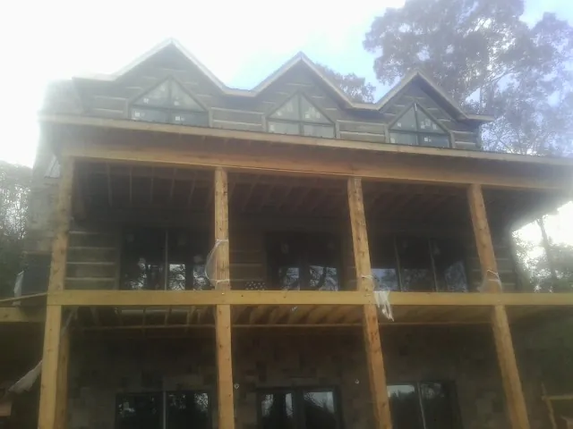 Dormers and porch framing on a large log home under construction — Roof Coating work by our crew in Bennington