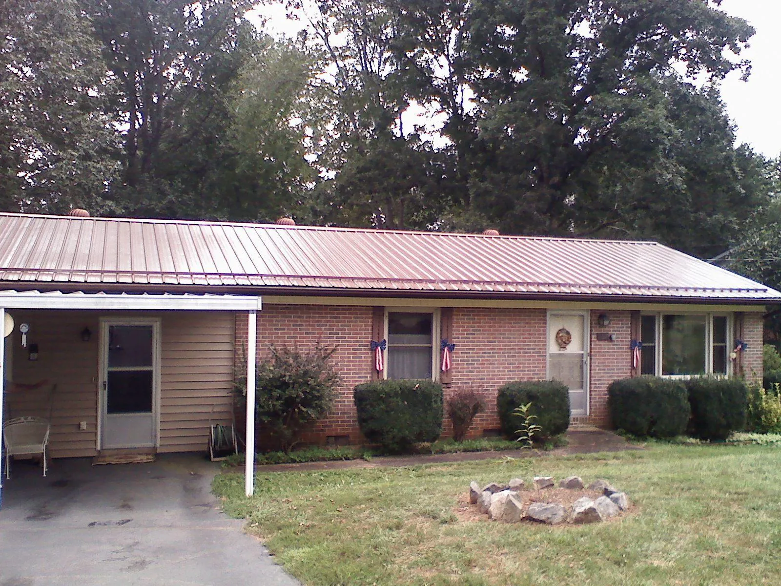 Bronze metal roof and carport on a brick ranch home — Roof Repair work by our crew in Bennington